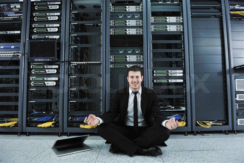 Young handsome business man in black suit and tie practice yoga and relax at network server room while representing stres control concept, stock photo