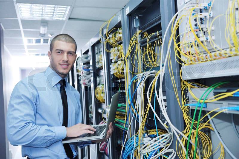 Young engeneer business man with thin modern aluminium laptop in network server room, stock photo