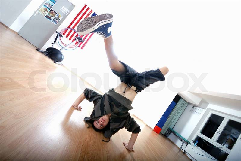 Young man performing break dance in dance studio, stock photo