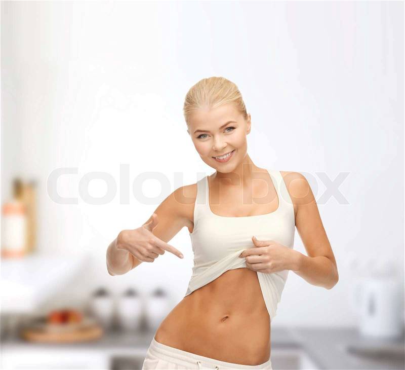 Fitness and diet concept - beautiful sporty woman pointing at her abs, stock photo