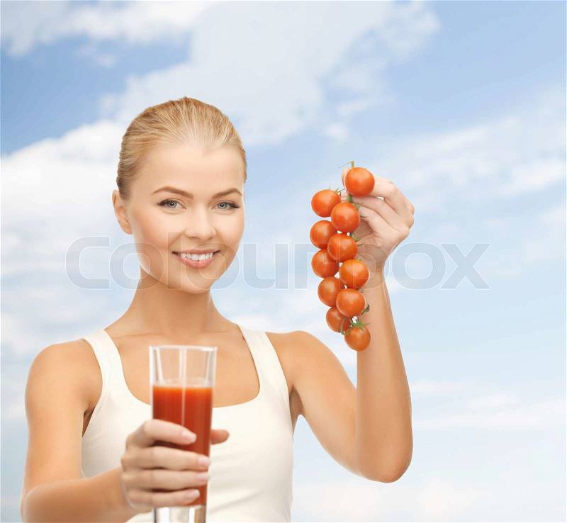 Fitness and diet concept - young woman holding glass of juice and tomatoes, stock photo