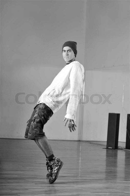 Young man performing break dance in dance studio, stock photo