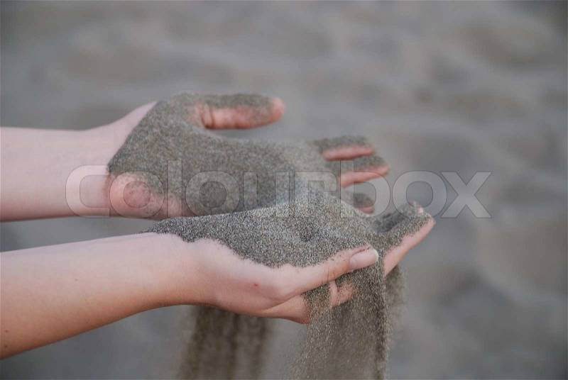Fine sand leaking trought woman hands, stock photo