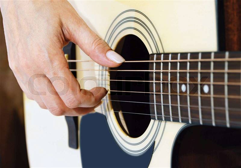 woman hand plucking strings on a guitar, stock photo