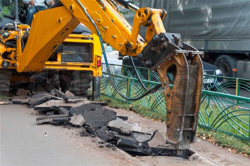 Road construction machine with the breaker dividing the asphalt, stock photo