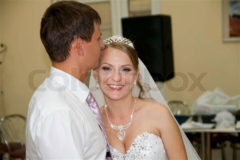 Bridegroom is pressed his lips to her forehead of the bride, stock photo