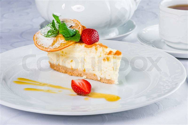 Piece of orange cheesecake with fresh mint and strawberry, stock photo