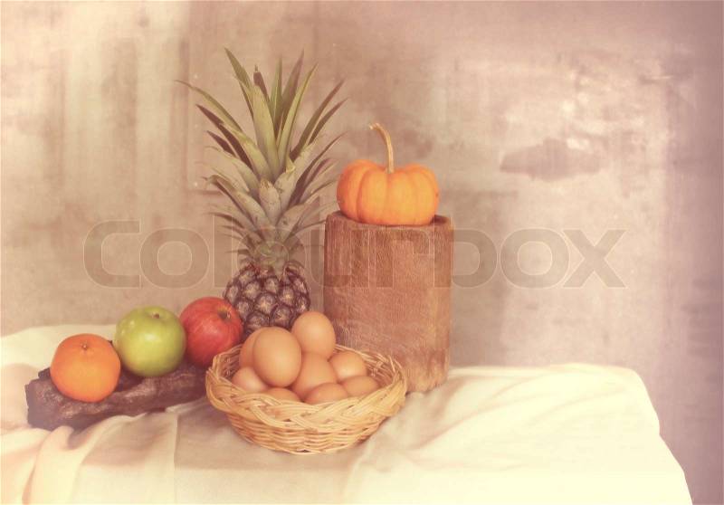 Still life apple, pineapple,pumpkin and basket of eggs in vintage style with delective focus, stock photo