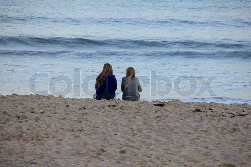 The sisters on the beach have a break and looking to the sea in the summer, stock photo