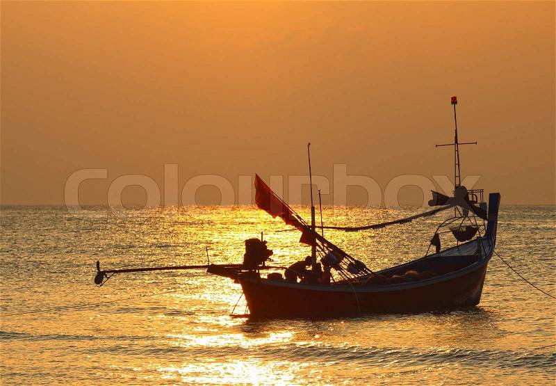 Stunning golden sunset over sea and sky with fishing boat floating, stock photo
