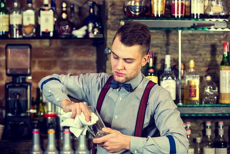 Young man working as a bartender in a nightclub bar, stock photo