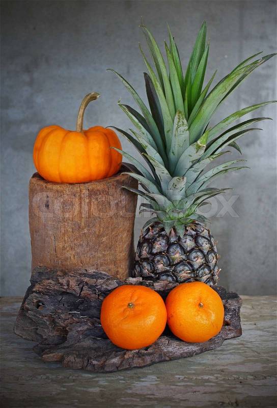 Still life pumpkin,pineapple and tangerine on antique wood board in vintage style, stock photo