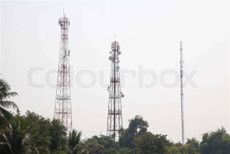 Telecommunications transmission towers Signals in space communication networks. There are a lot of tree cover in the area, stock photo
