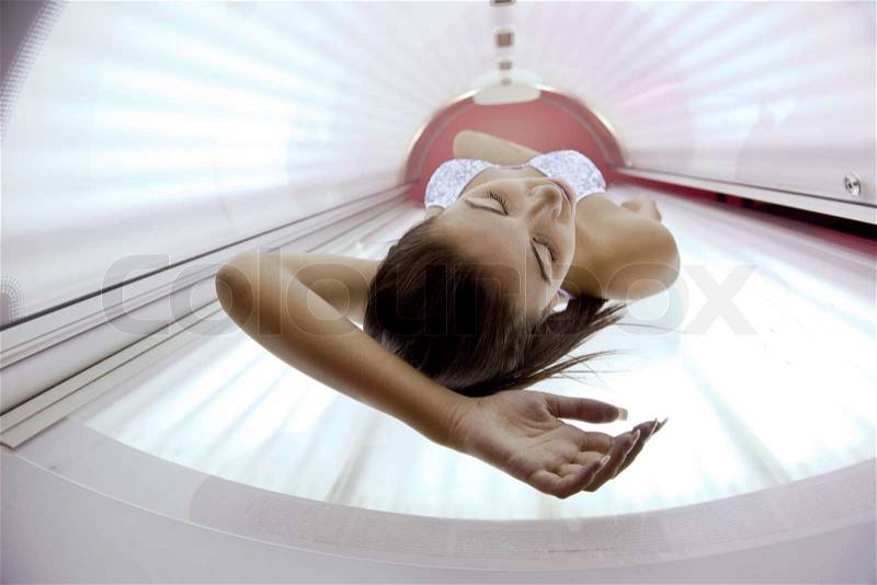 Beautiful young woman have tanning skin treatment in modern solarium, stock photo