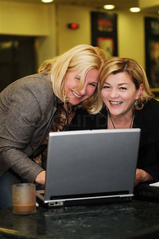 Two happy mature senior business woman work on laptop computer, stock photo