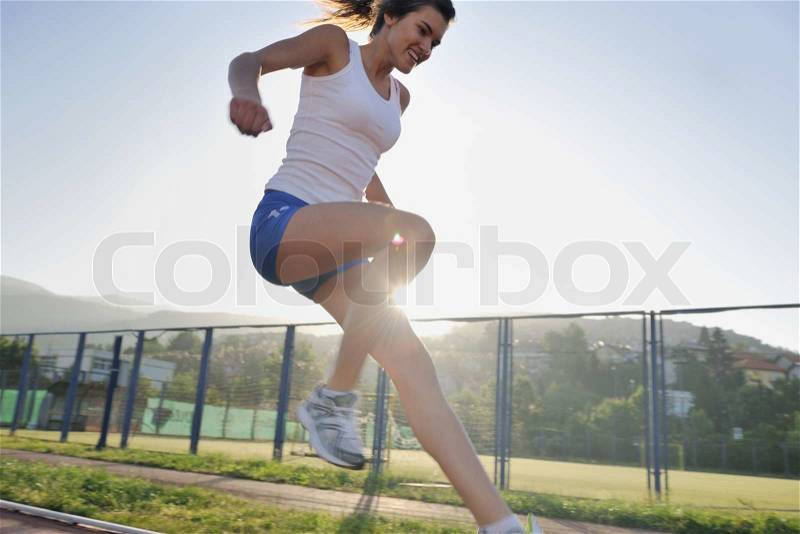 Beautiful young woman exercise jogging and runing on athletic track on stadium at sunrise , stock photo