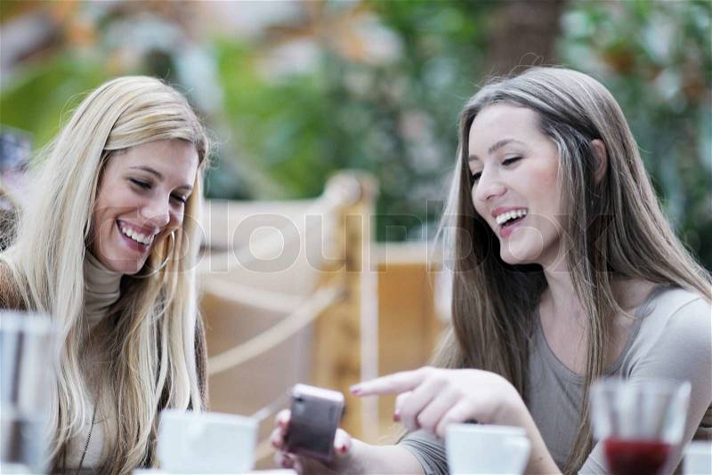 Very cute smiling women drinking a coffee sitting inside in cafe restaurant, stock photo