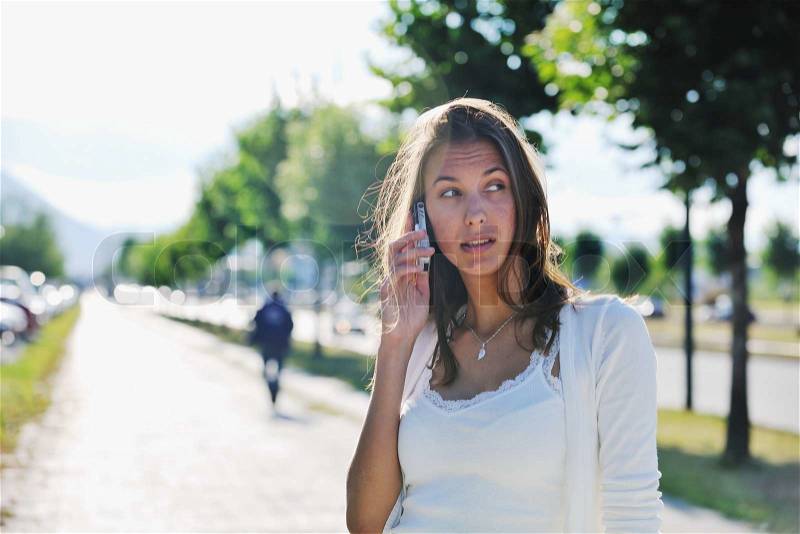 Beautiful fit young woman talk by cellphone in city at street on sunny day, stock photo