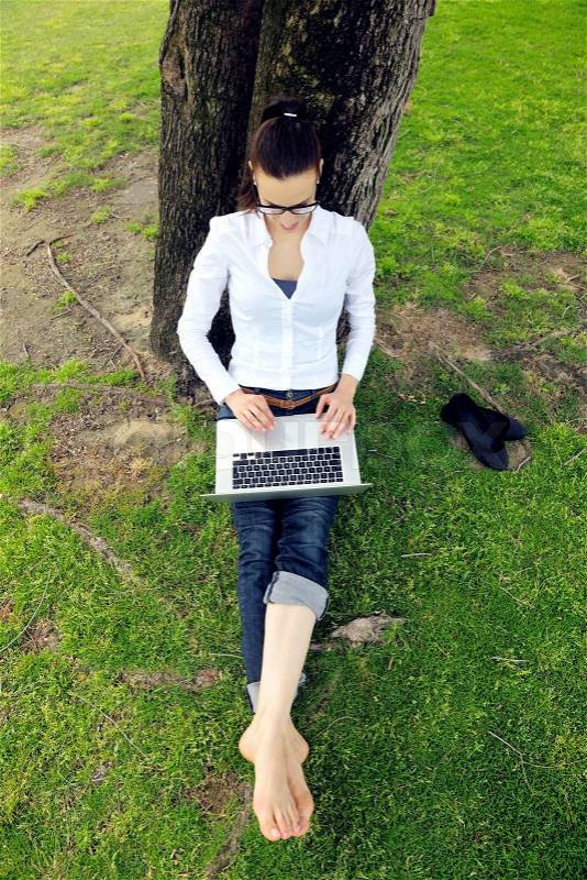 Happy young student woman with laptop in city park study, stock photo