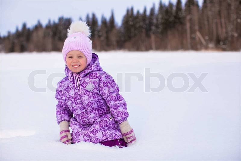 Little happy adorable girl having fun on the snow at winter sunny day, stock photo