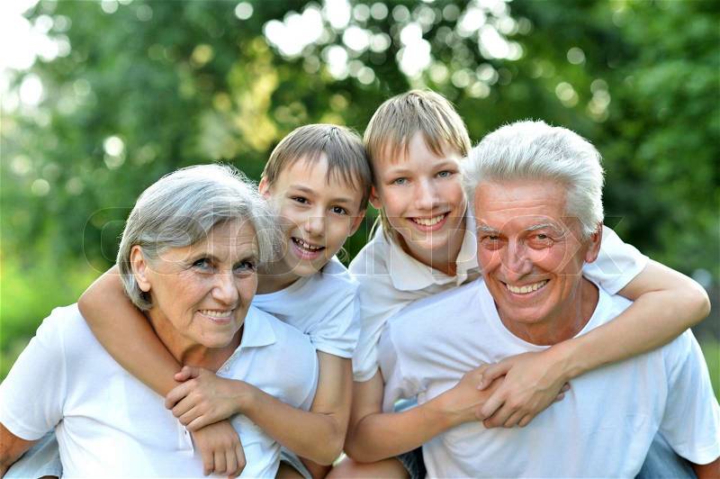 Older man and woman with their grandchildren having fun outdoors, stock photo