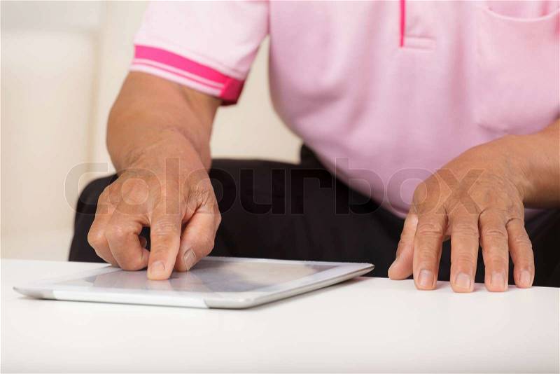 Senior man using digital tablet at home, stock photo