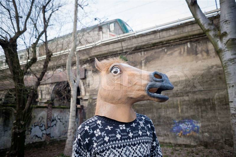 Young hipster man horse mask at the park, stock photo