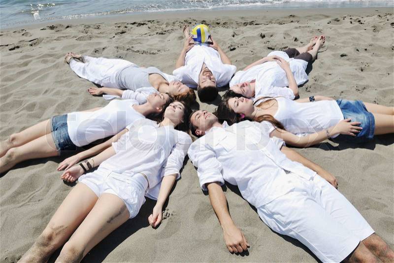 Group of happy young people in circle at beach have fun, stock photo