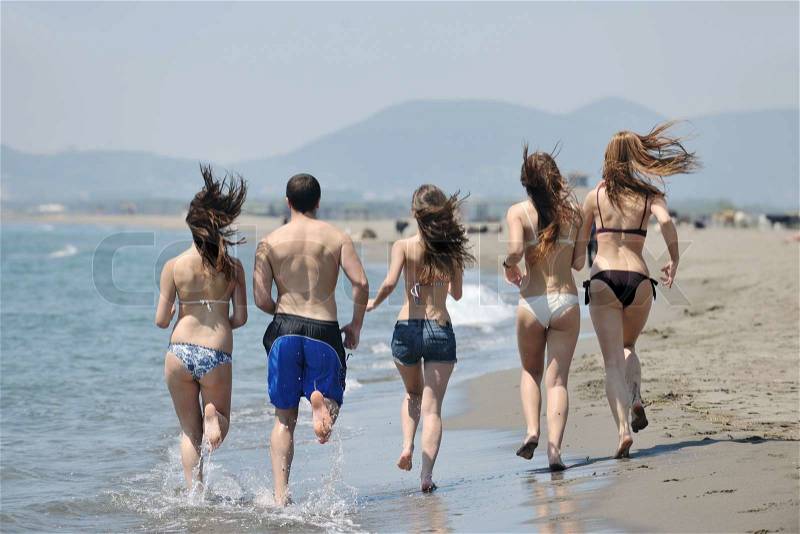 Happy young people group have fun run and jump on beach beautiful sand beach, stock photo