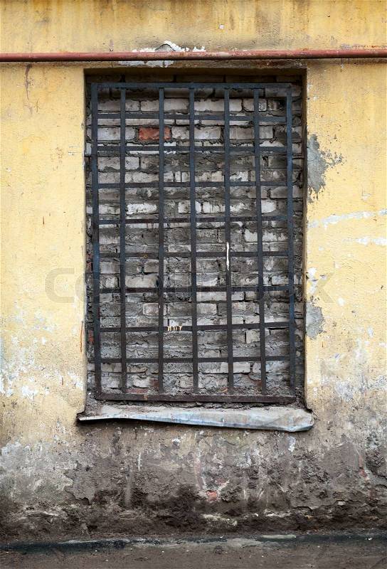 Old yellow building facade with locked window, stock photo