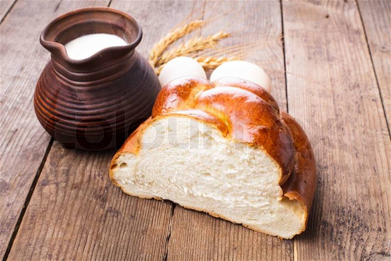 Fresh loaf of challah with milk and eggs on the table, stock photo