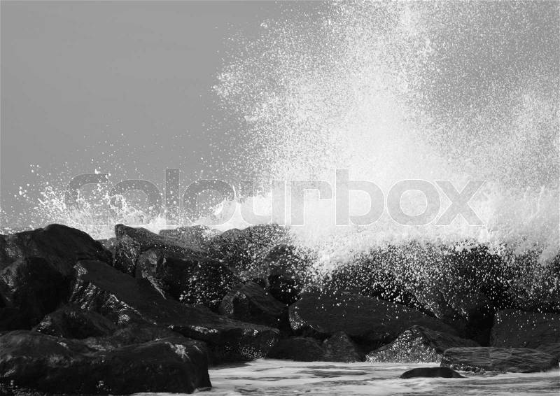 Crashing waves against black rocks at coast, stock photo