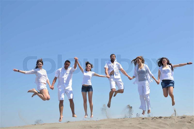 Happy people group have fun run and jump on beach beautiful sand beach, stock photo