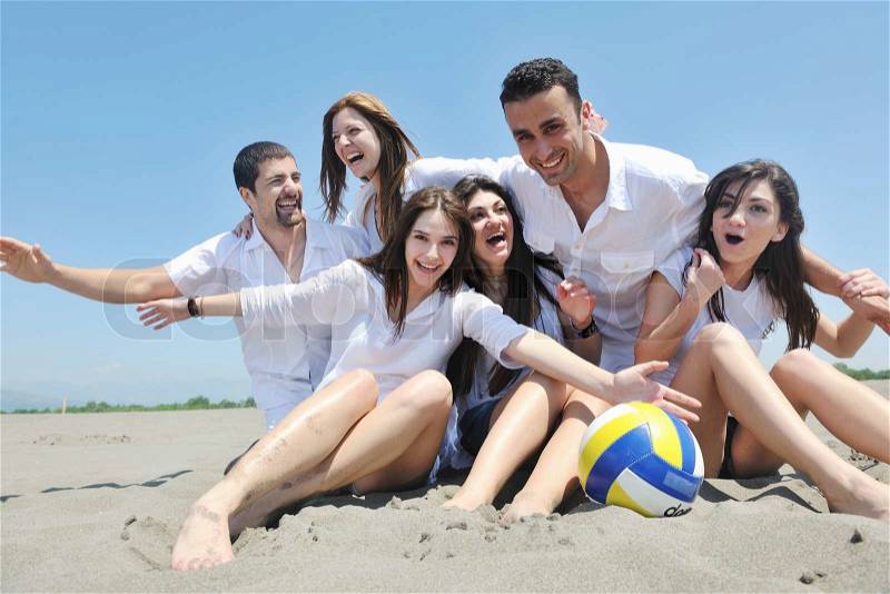 Group of happy young people in circle at beach have fun, stock photo