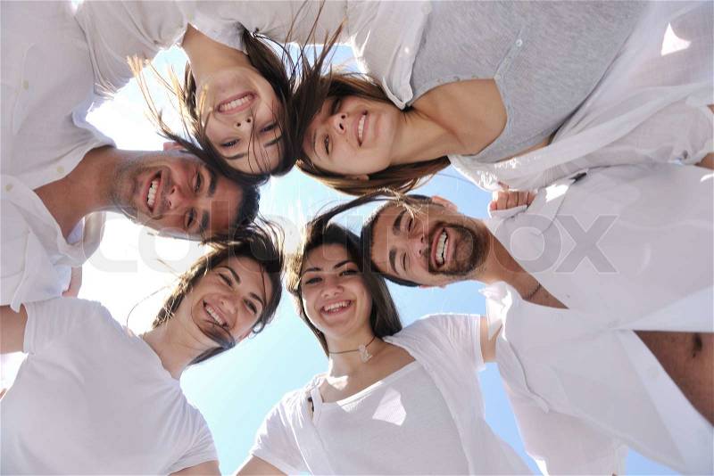 Group of happy young people in circle at beach have fun and smile, stock photo