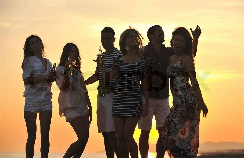 Group of young people enjoy summer party at the beach on beautiful sunset, stock photo
