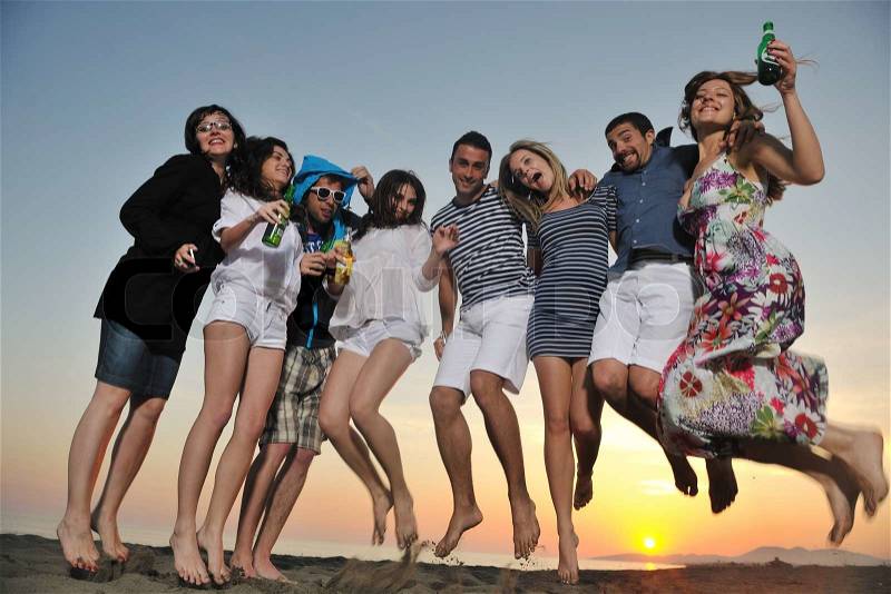 Group of young people enjoy summer party at the beach on beautiful sunset, stock photo