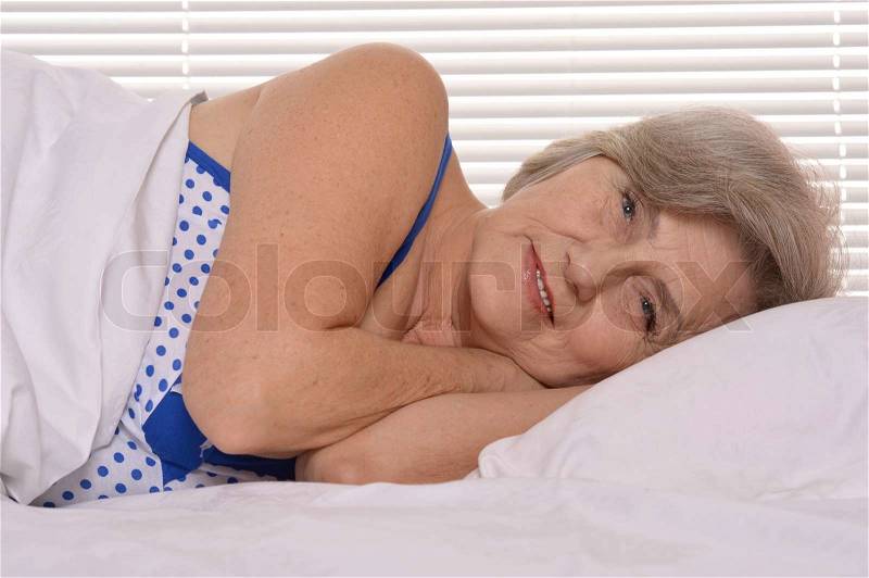 Beautiful older woman resting in the bedroom after a hard working week, stock photo
