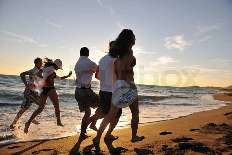 Happy young people group have fun white running and jumping on beacz at sunset time, stock photo