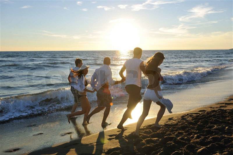 Happy young people group have fun white running and jumping on beacz at sunset time, stock photo