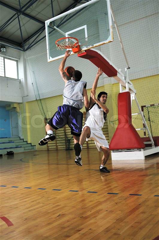Competition cencept with people who playing basketball in school gym, stock photo
