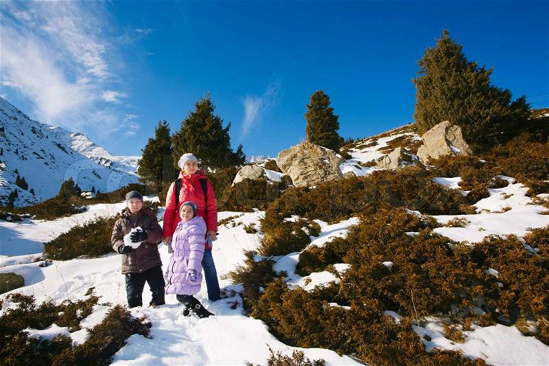 Family (mother with two children) take a walk on winter mountain slope (Big Almaty Lake, Kazakhstan), stock photo