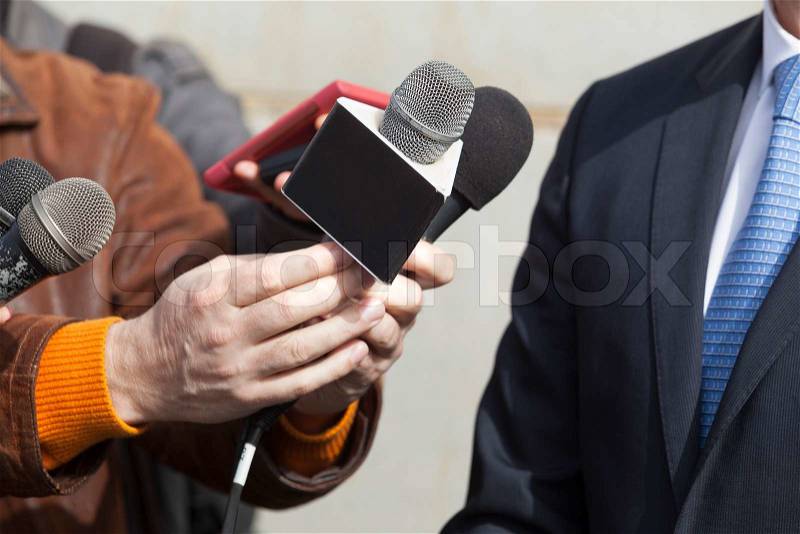Interview with media microphone held in front of businessman, spokesman or politician, stock photo
