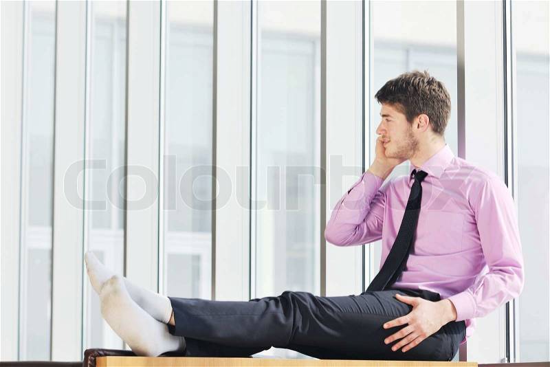 Young business man talk by cellphone over bright window in big hall, stock photo