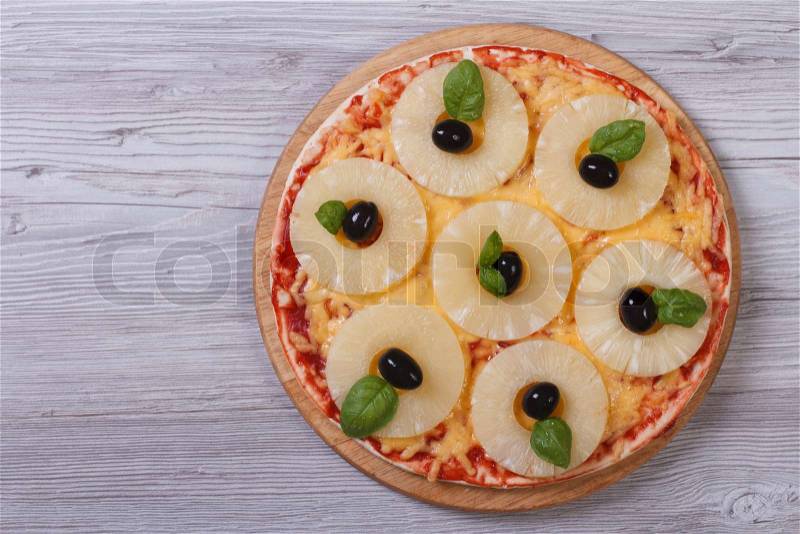 Pizza with pineapple rings, olives and basil on the table. top view , stock photo