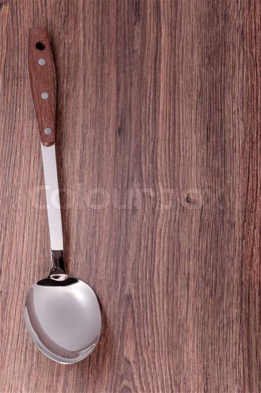 Serving spoon with a wooden handle on the background of the tree, stock photo
