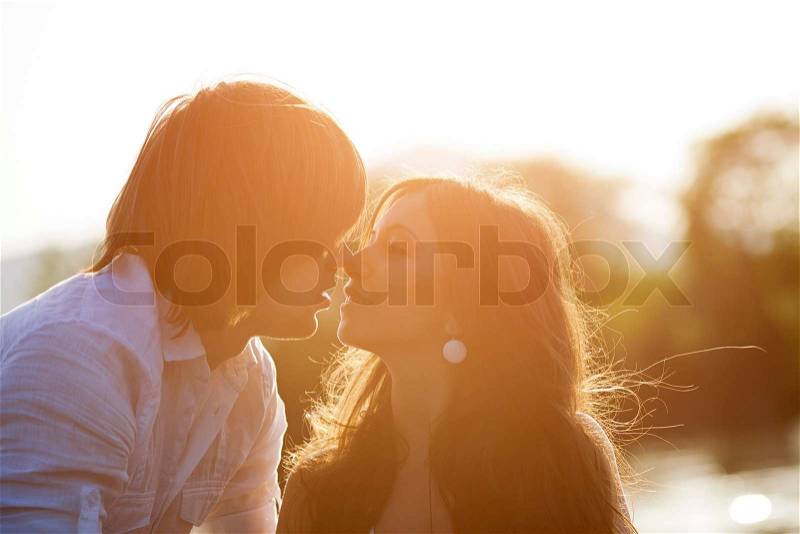 Young people kissing on sunset, stock photo