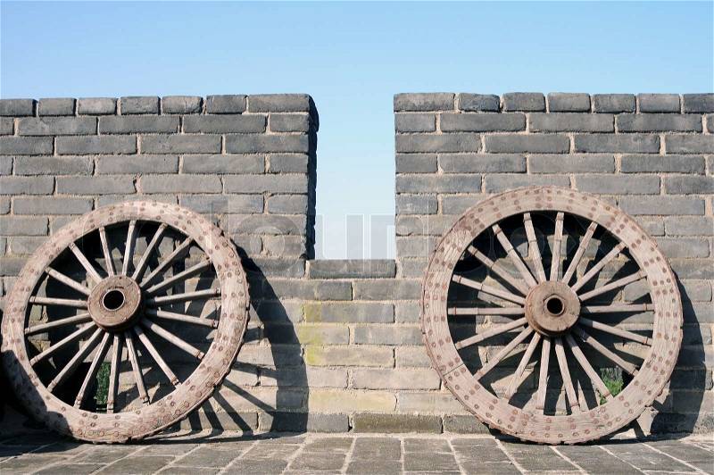 Ancient carriage wheel against brick wall, stock photo