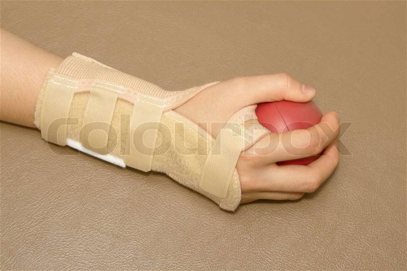 Woman\'s hand with wrist support squeezing a soft ball for hand rehabilitation, stock photo