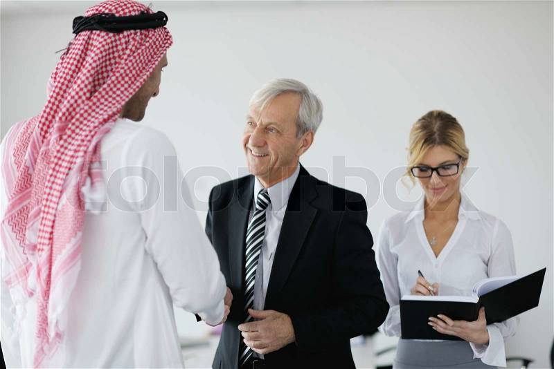 Business meeting - Handsome young Arabic man presenting his ideas to colleagues and listening for ideas for success investments at bright modern office room, stock photo